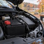Стартерный аккумулятор под капотом автомобиля с закрытым защитным колпачком клеммы