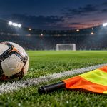 Футбольный мяч и флаг помощника судьи у белой линии поля